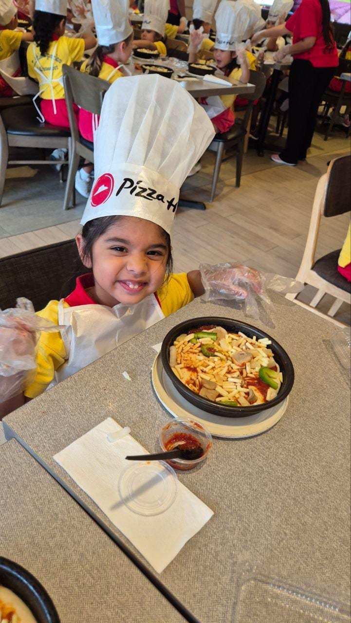 Child in a chef hat with a homemade pizza