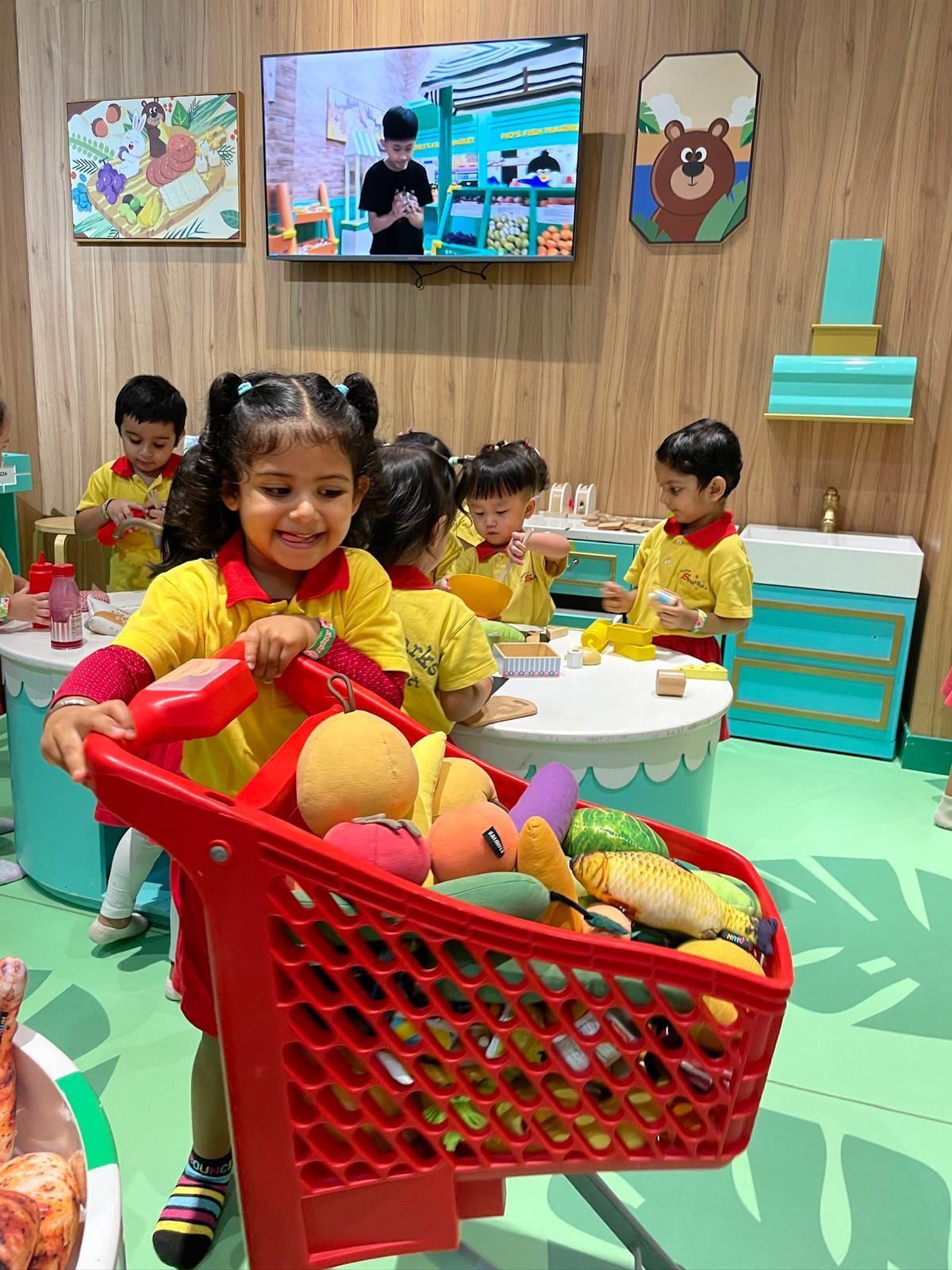 Children at the play kitchen with a basket of play food