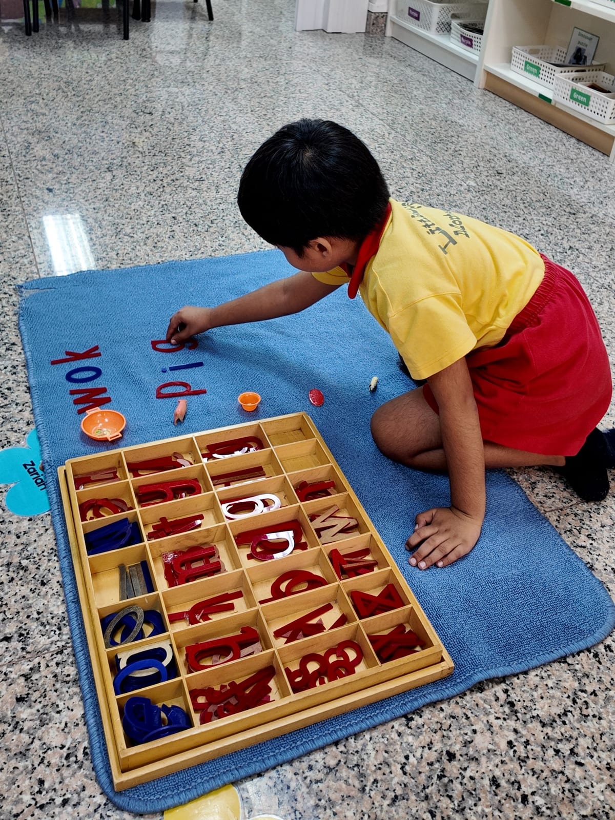A child spelling words with the Montessori movable alphabet