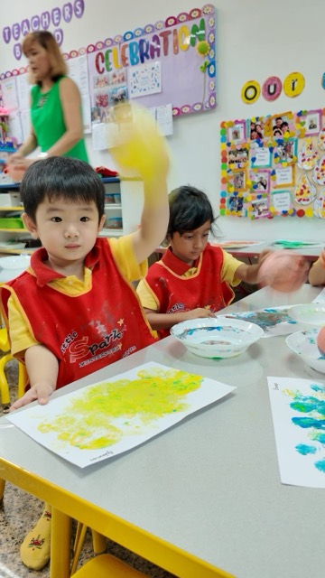 A child proudly showing their artwork